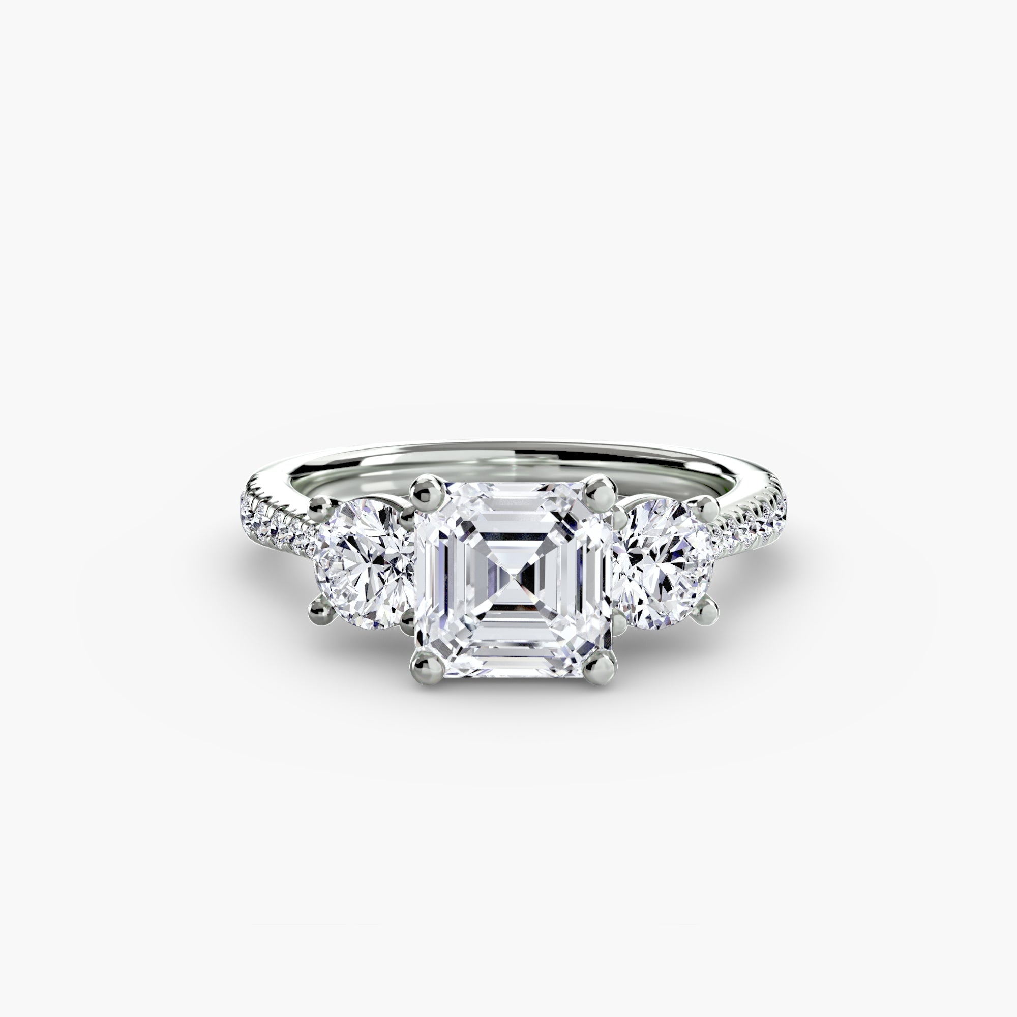 The MICHAEL ISAAC Three-Stone with Pavé Band features a platinum setting with a square emerald-cut center diamond and two round side diamonds, all on a pavé band, shown against a white background.