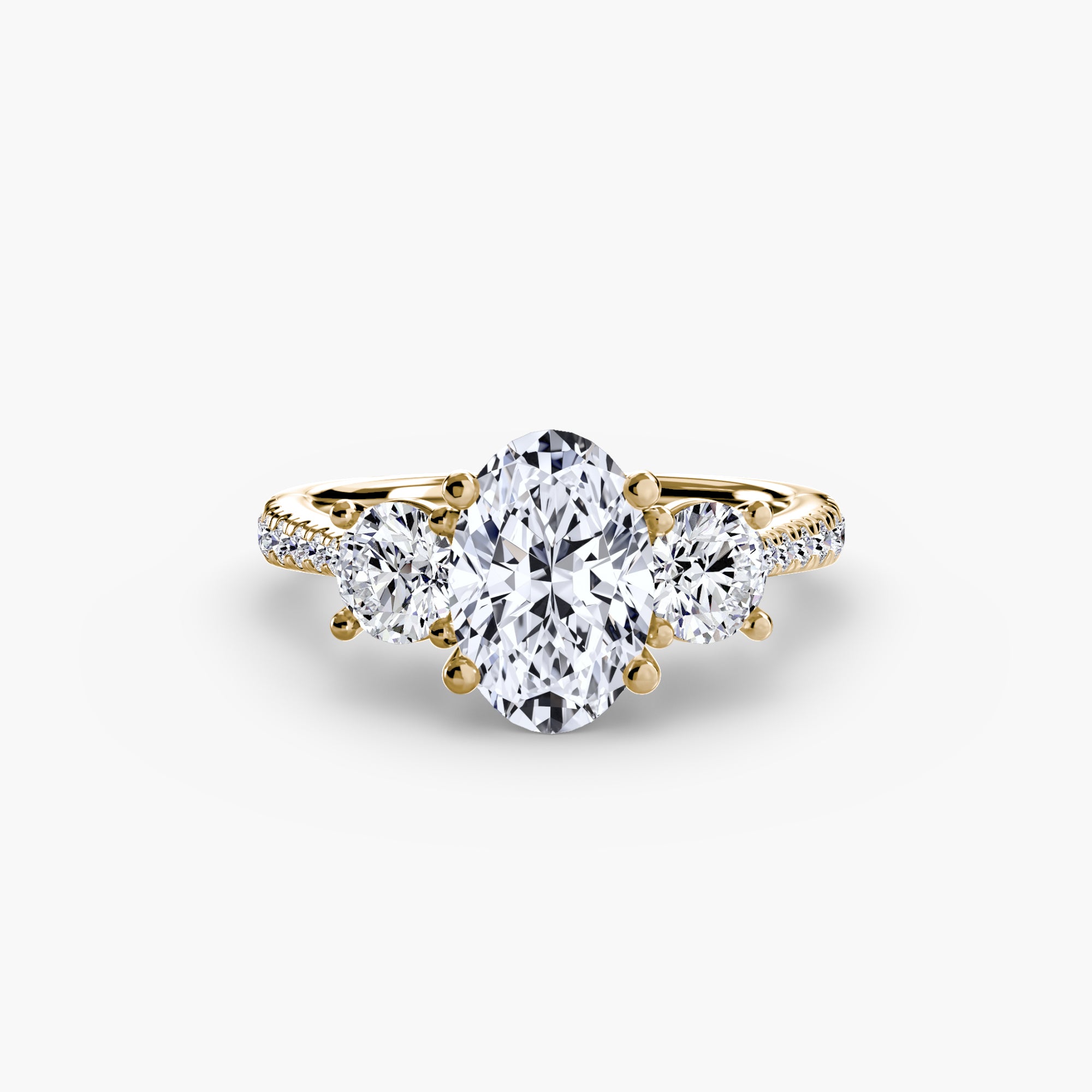 The MICHAEL ISAAC Three-Stone with Pavé Band ring features an oval-cut center diamond, two round side diamonds, and a pavé band set in gold, all showcased against a plain white background.
