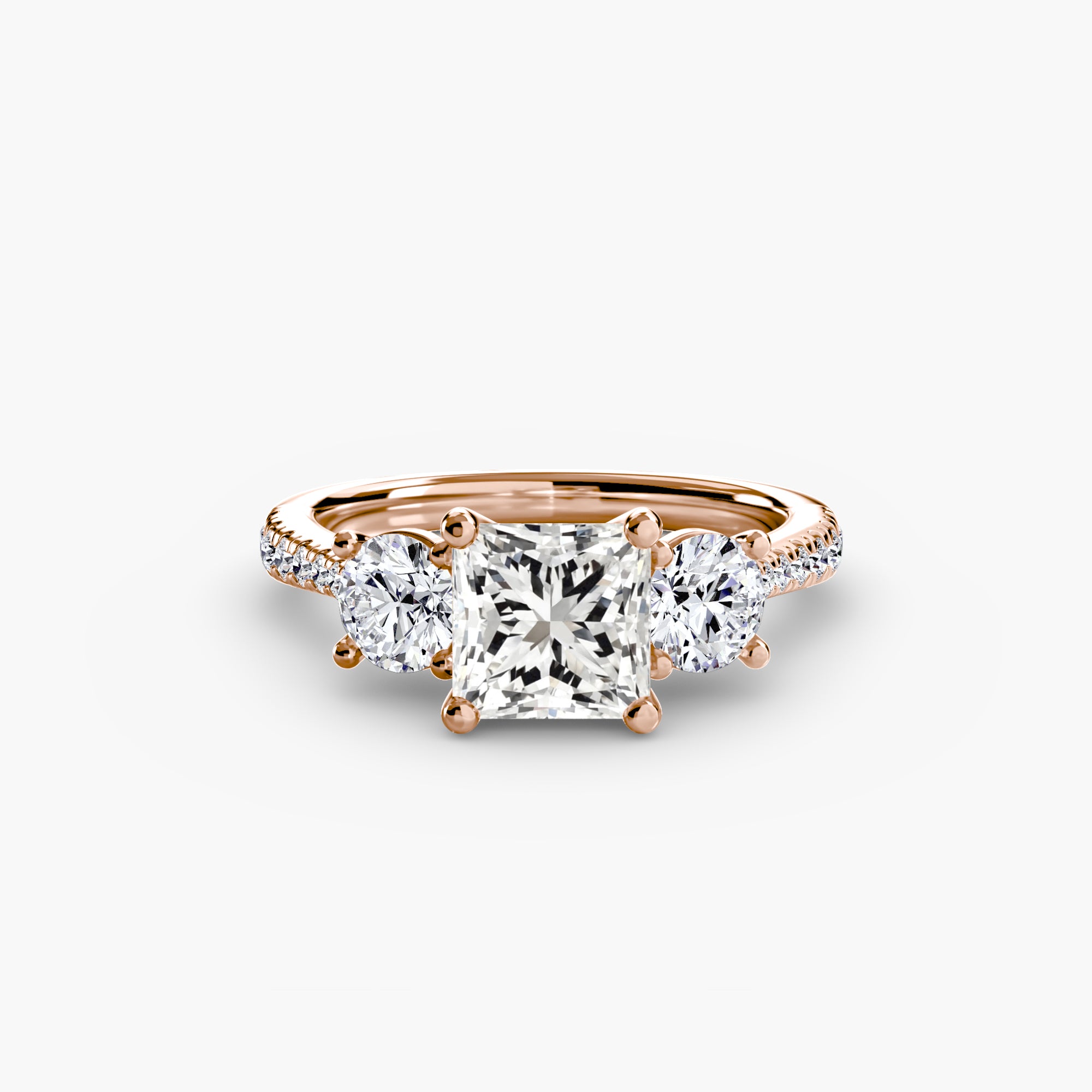The MICHAEL ISAAC Three-Stone with Pavé Band features a rose gold ring with a large square-cut center diamond, two oval side diamonds, and pavé diamonds along the band, showcased against a plain white background.