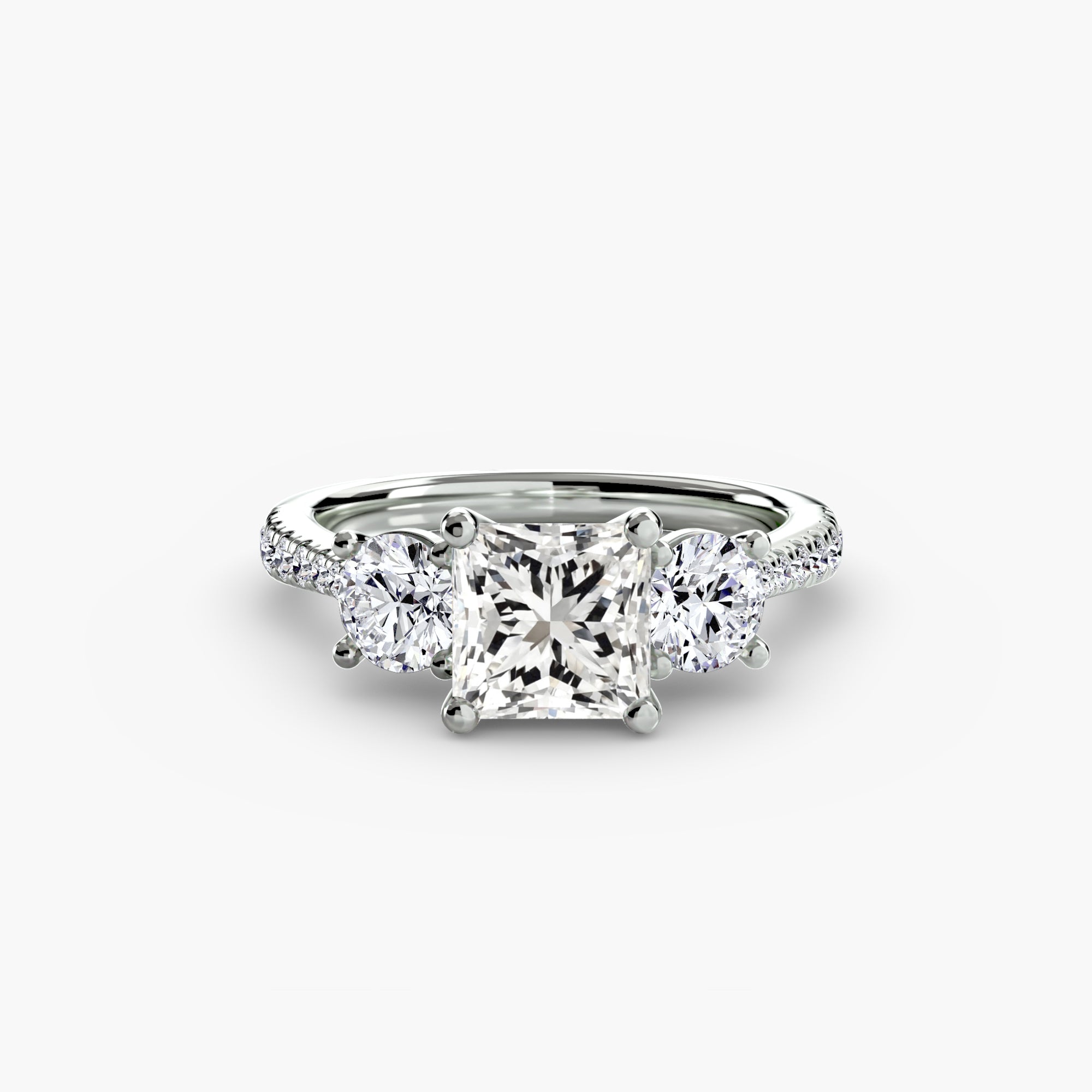 The MICHAEL ISAAC Three-Stone with Pavé Band features a striking square-cut center diamond, two side round diamonds, and pavé-set stones along the band for added brilliance.