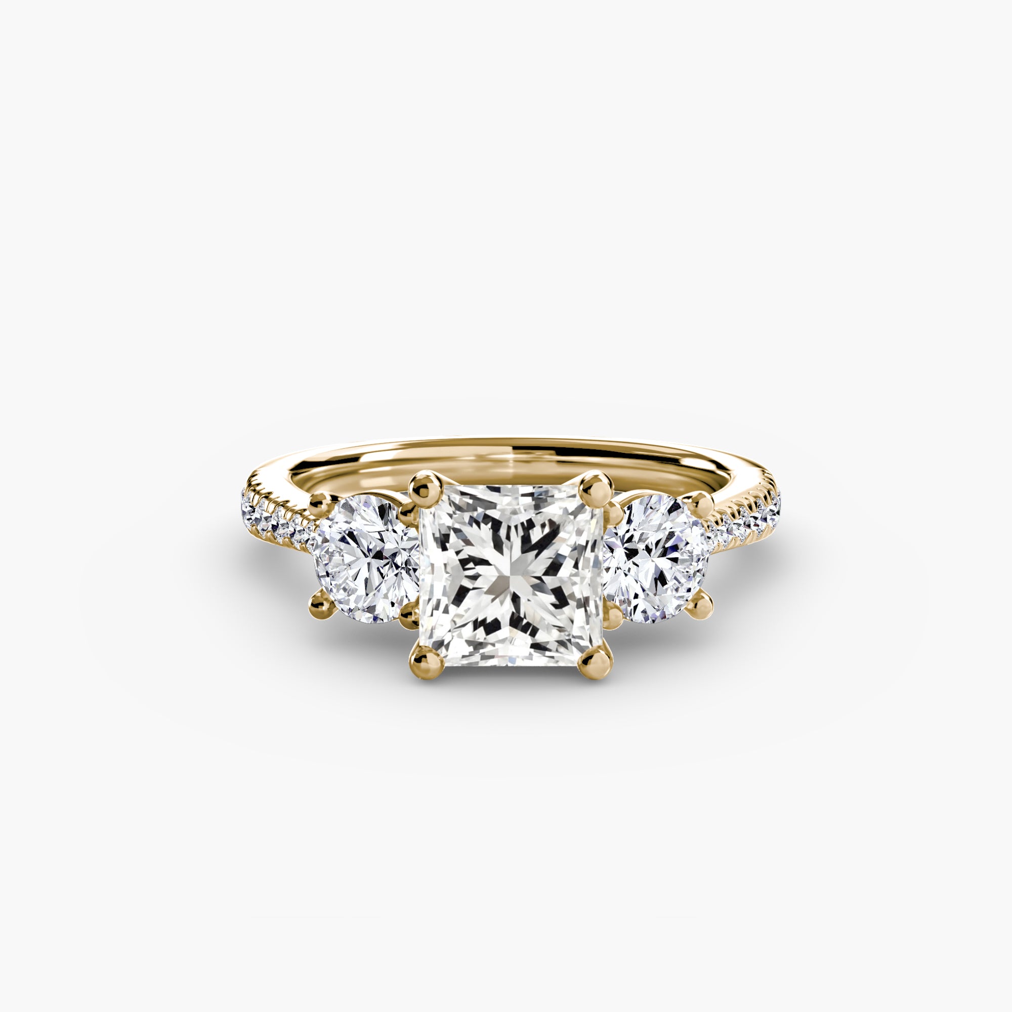 The Three-Stone with Pavé Band by MICHAEL ISAAC is an elegant gold engagement ring featuring a square-cut center diamond, two round side stones, and a pavé diamond band.