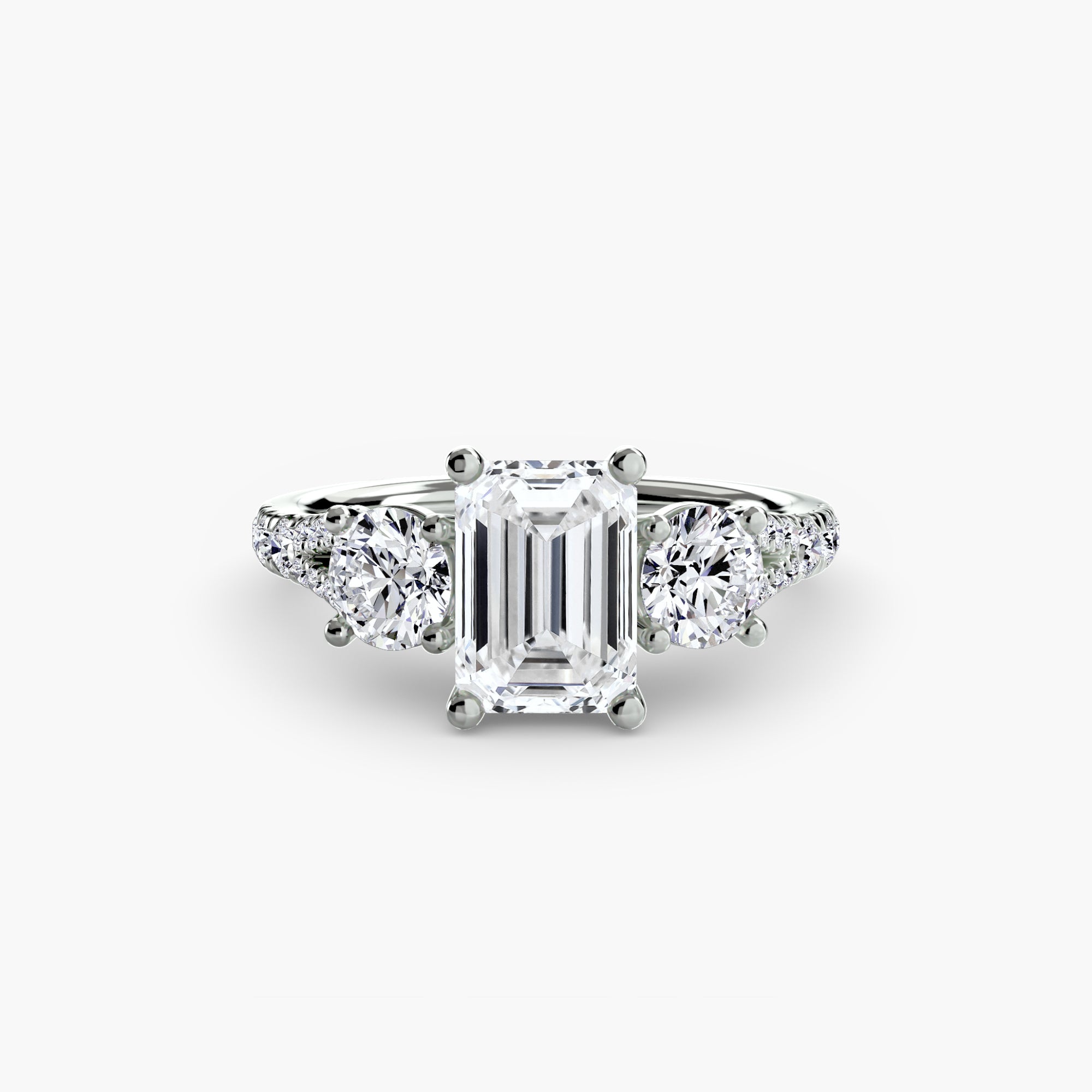 The Three-Stone with Pavé Band 3 ring by MICHAEL ISAAC features a central emerald-cut diamond flanked by round diamonds, displayed on a plain white background.