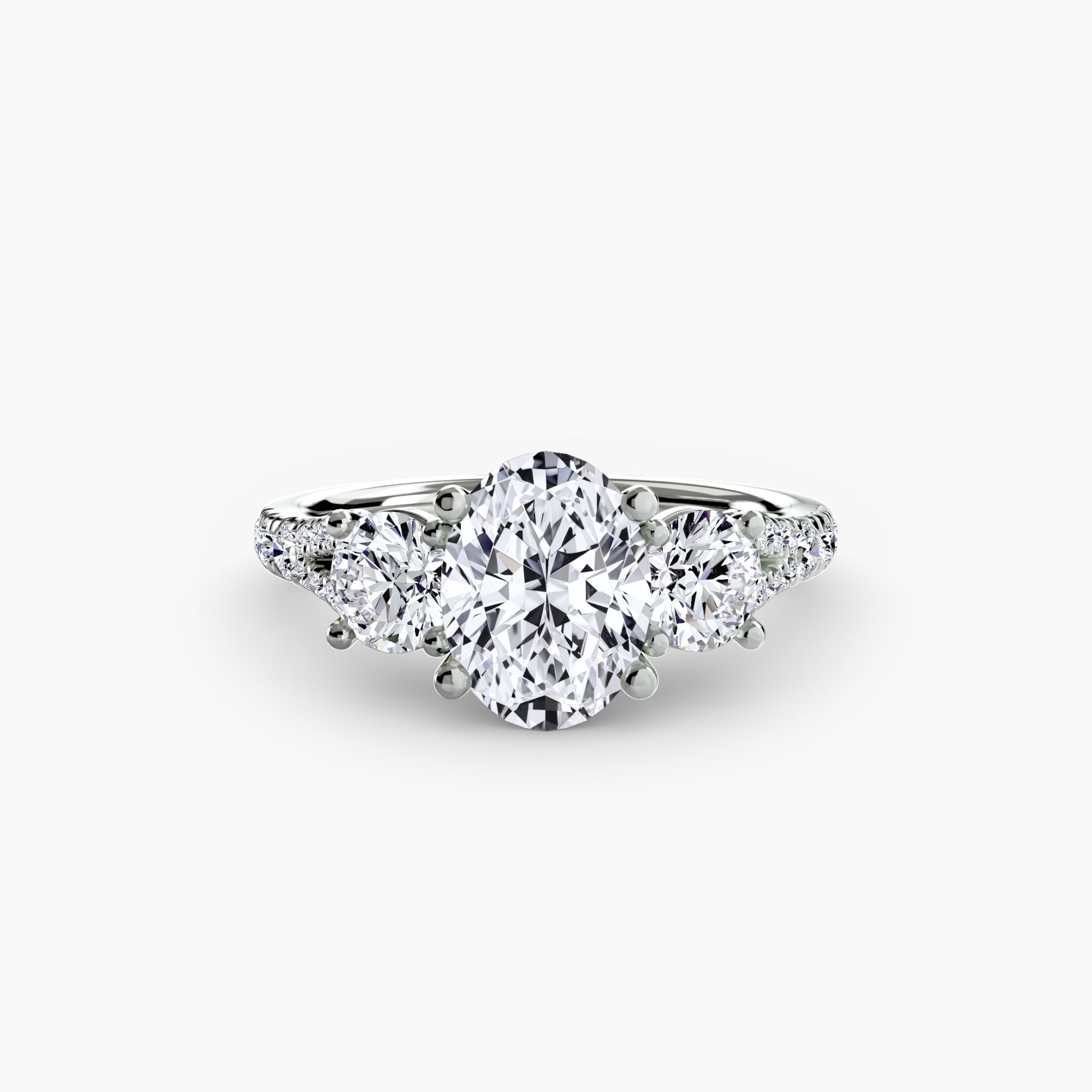 The MICHAEL ISAAC Three-Stone with Pavé Band 3 ring in white gold showcases an oval-cut center diamond, two round side diamonds, and pavé accent stones, elegantly set against a plain white background.