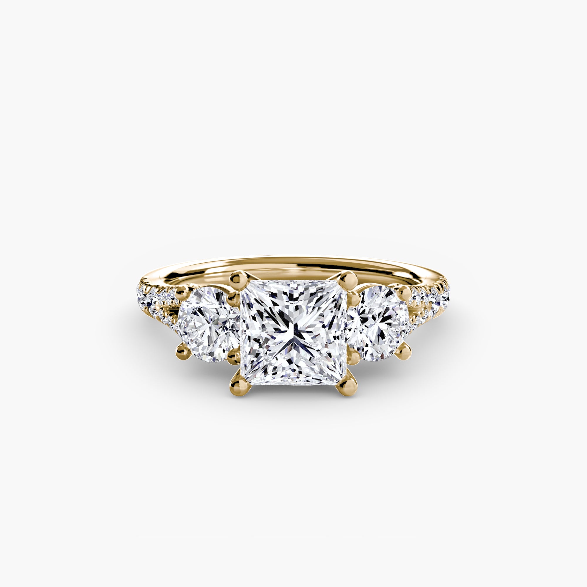 The MICHAEL ISAAC Three-Stone with Pavé Band 3 is a gold ring showcasing a large square-cut center diamond, two smaller round side diamonds, and pavé diamonds on the band, set against a plain white background.