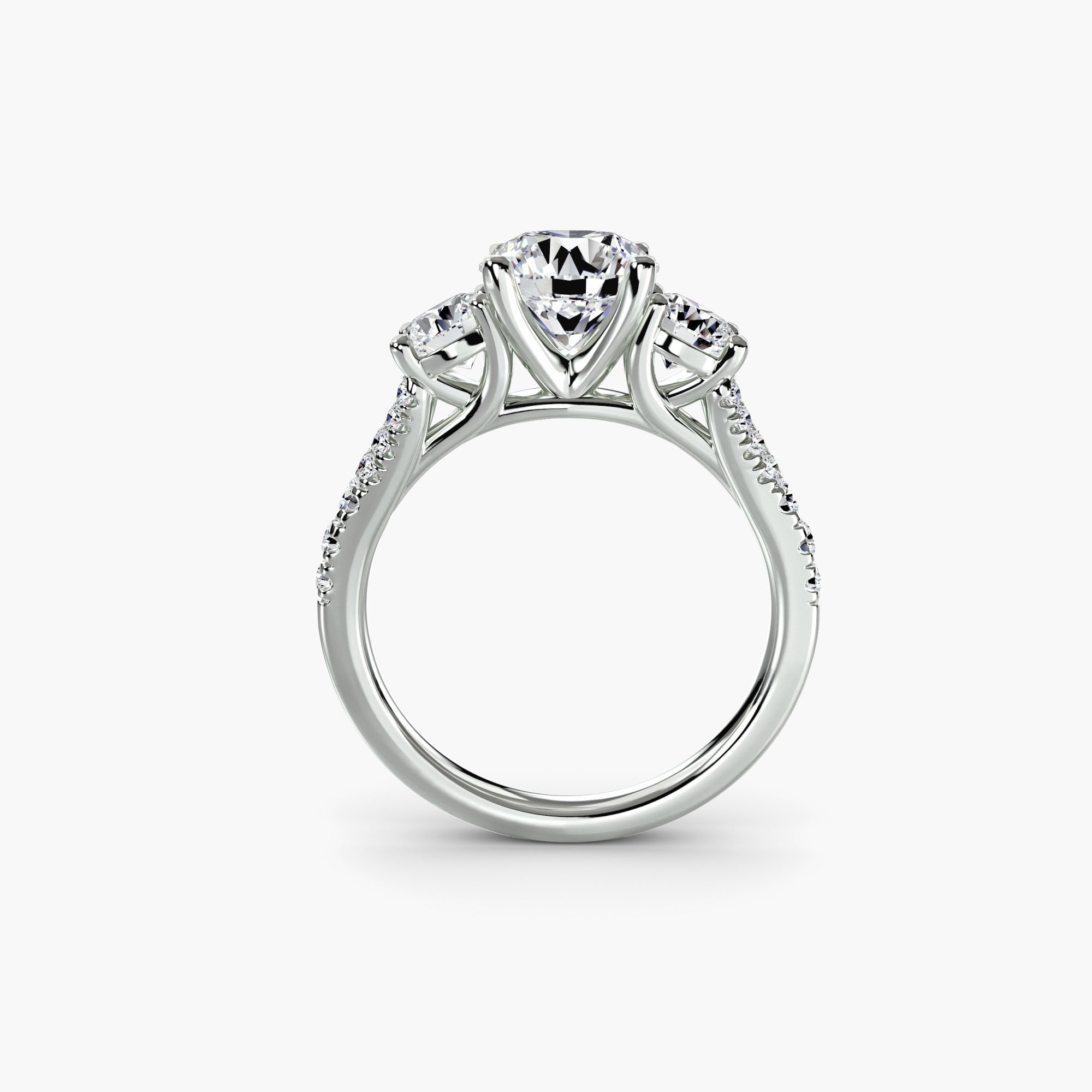 The MICHAEL ISAAC Three-Stone with Pavé Band 3 is a white gold ring featuring round diamonds atop and smaller pavé-set diamonds on the band, shown against a plain white background.