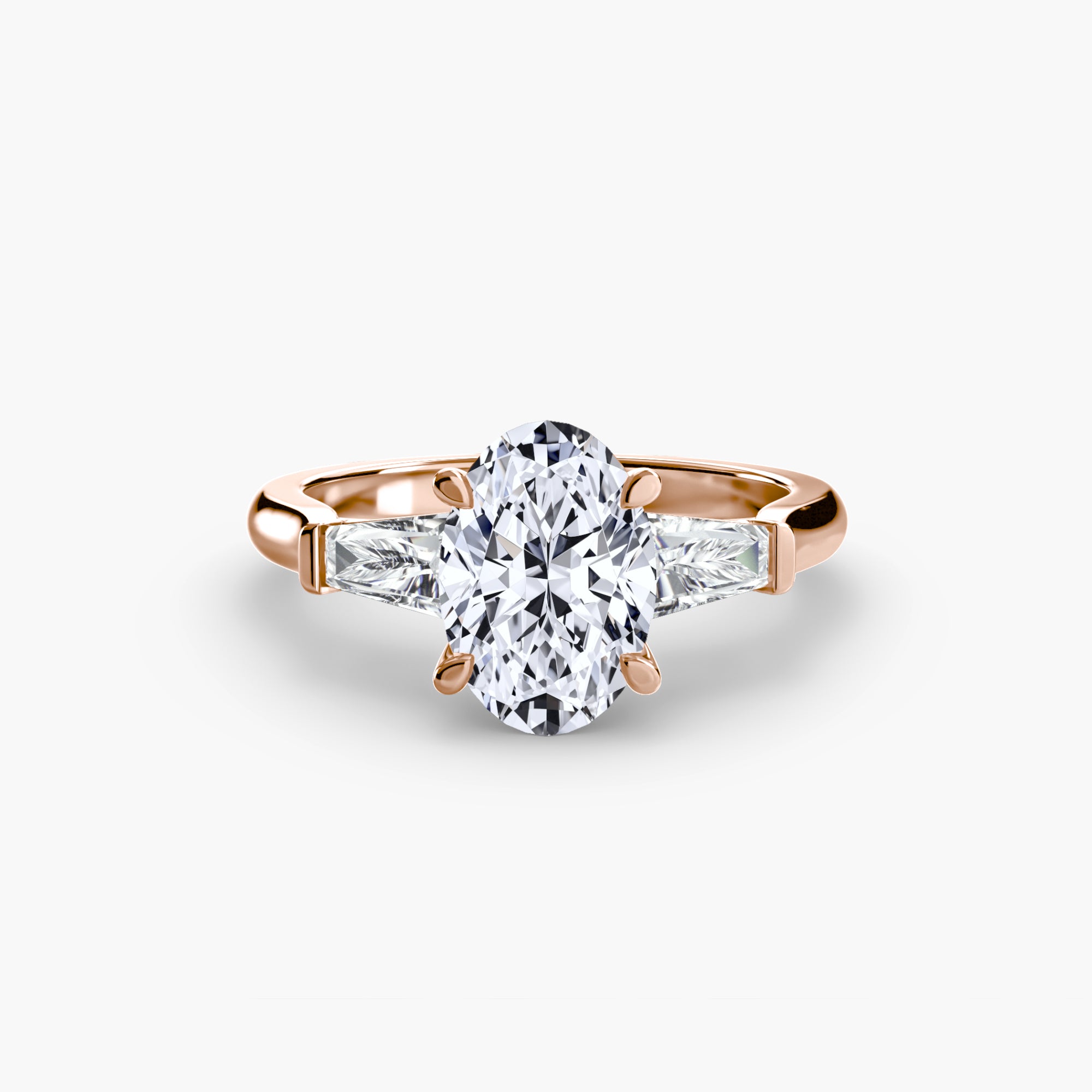 The MICHAEL ISAAC Three-Stone Ring features a rose gold band with an oval center diamond and baguette side stones, displayed on a plain white background.