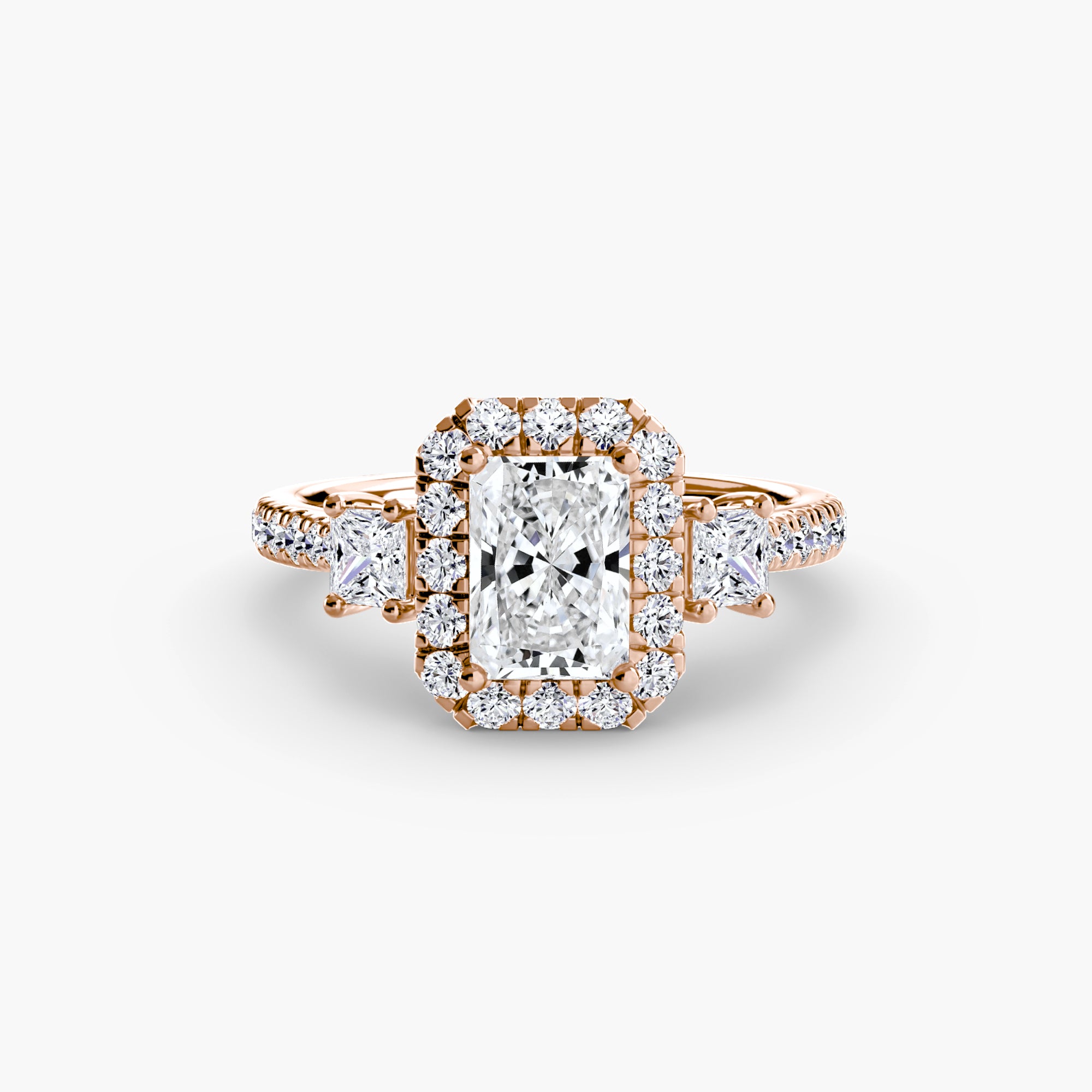 The MICHAEL ISAAC Three-Stone Ring with Halo 2 features a radiant-cut center diamond, haloed by smaller diamonds and flanked by side stones on the band, all set against a white background.