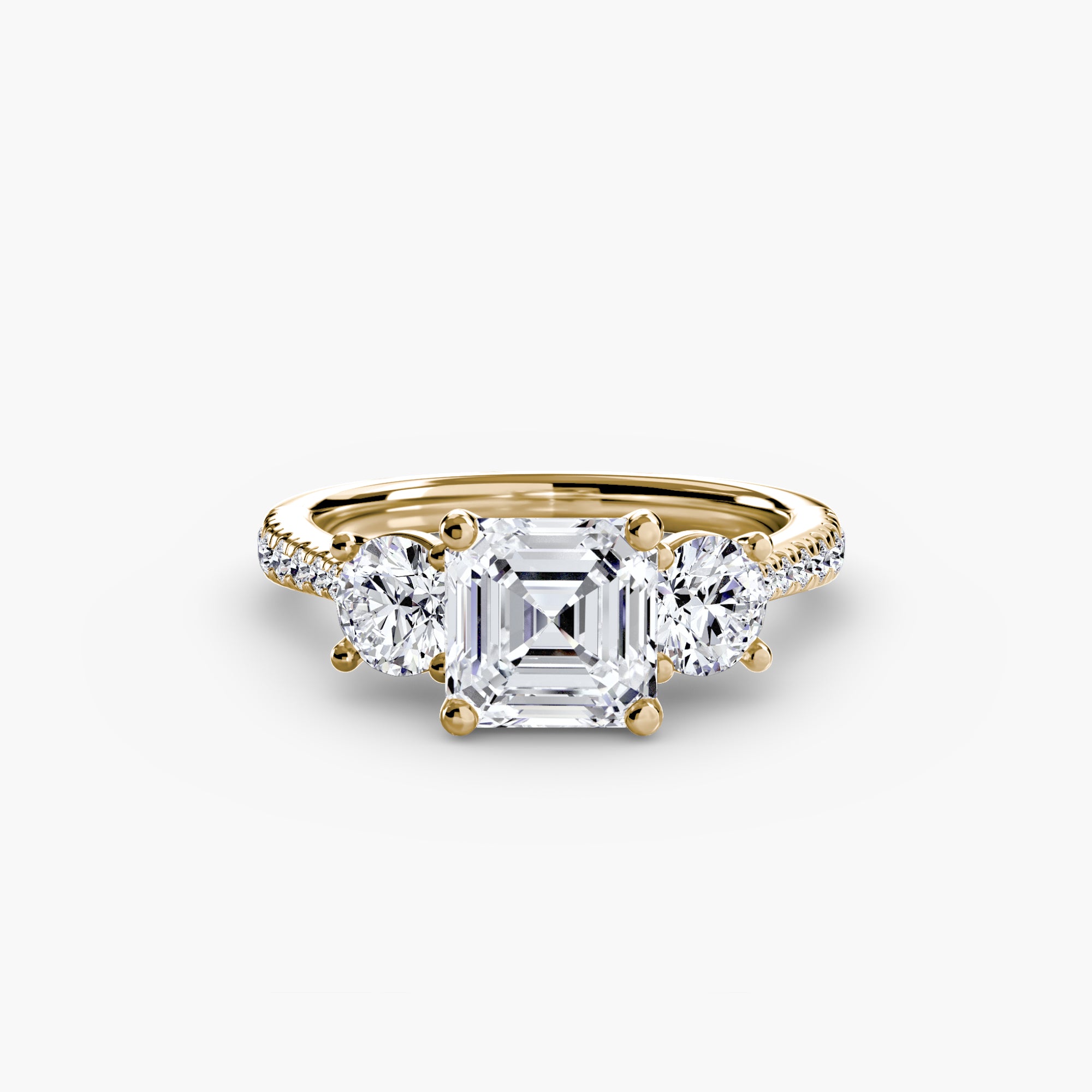 The Three-Stone with Pavé Band by MICHAEL ISAAC features a large square-cut center diamond, two round side diamonds, and additional diamonds set along the pavé band for an elegant and symmetrical look.