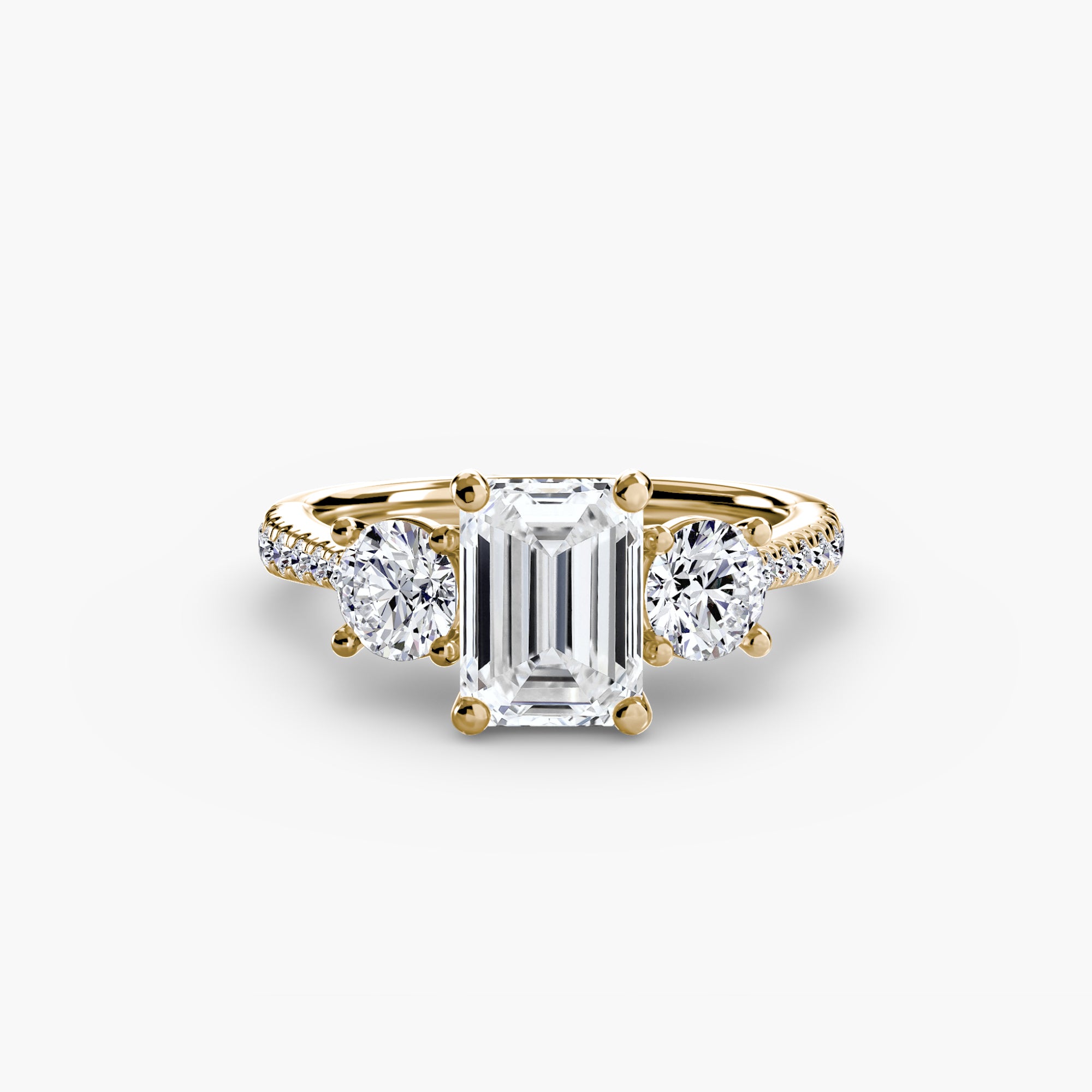 The MICHAEL ISAAC Three-Stone with Pavé Band features an emerald-cut center diamond, two round side diamonds, and a pavé band for added sparkle.