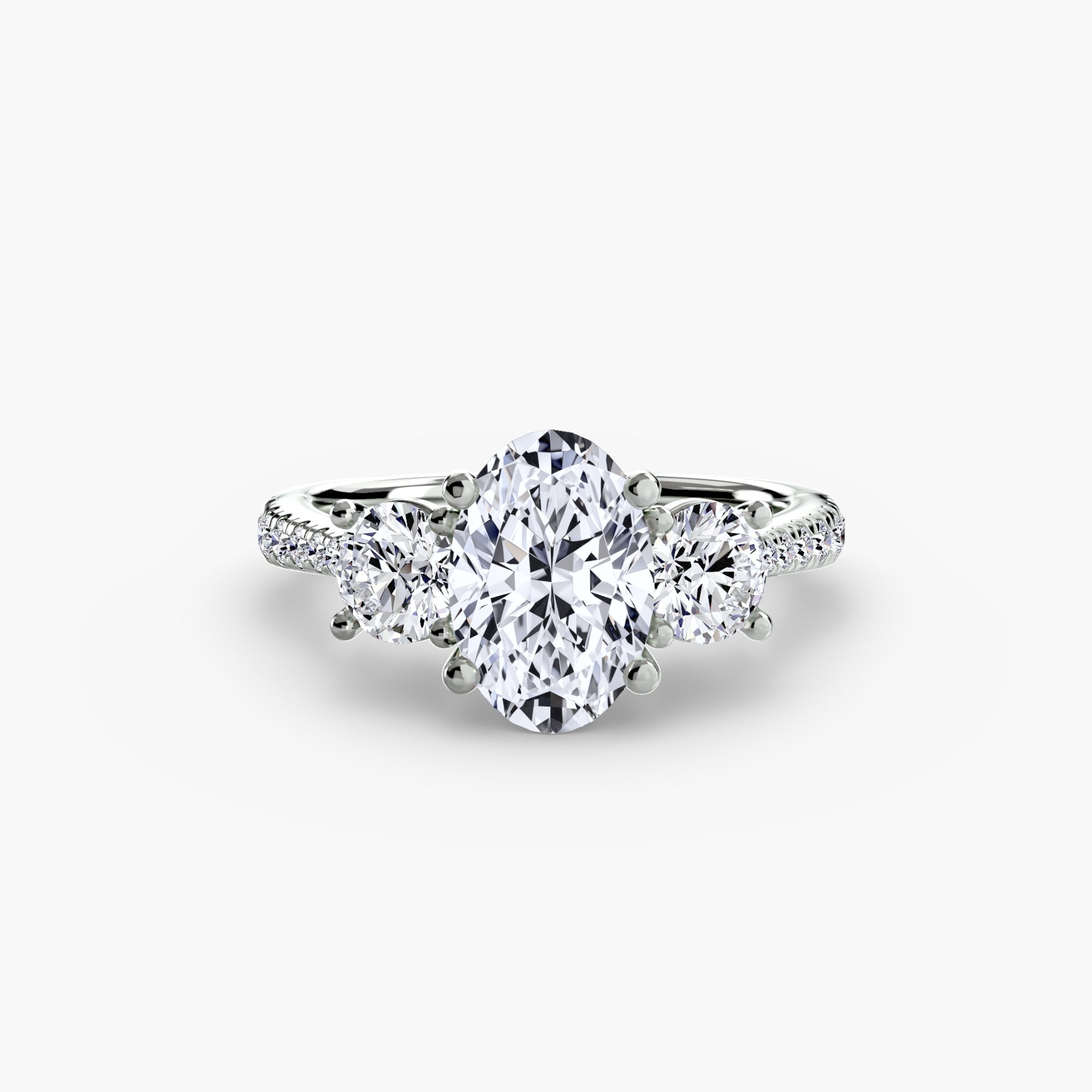 The MICHAEL ISAAC Three-Stone with Pavé Band ring features an oval-cut center diamond, two round side diamonds, and pavé-set diamonds along a white gold band, shown on a plain white background.
