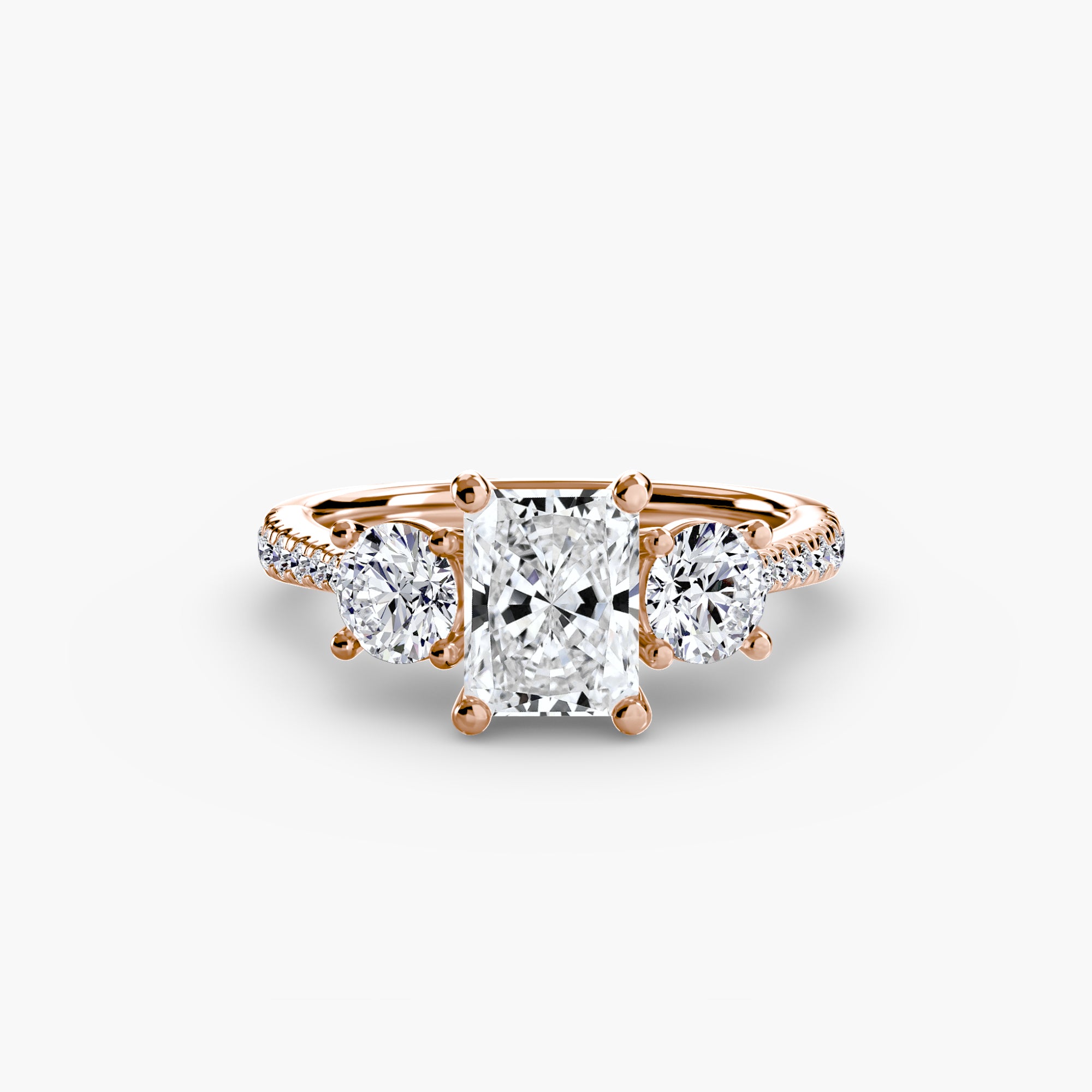 The MICHAEL ISAAC Three-Stone with Pavé Band is a rose gold ring with a radiant-cut center diamond, two round side stones, and pavé-set diamonds along the band.