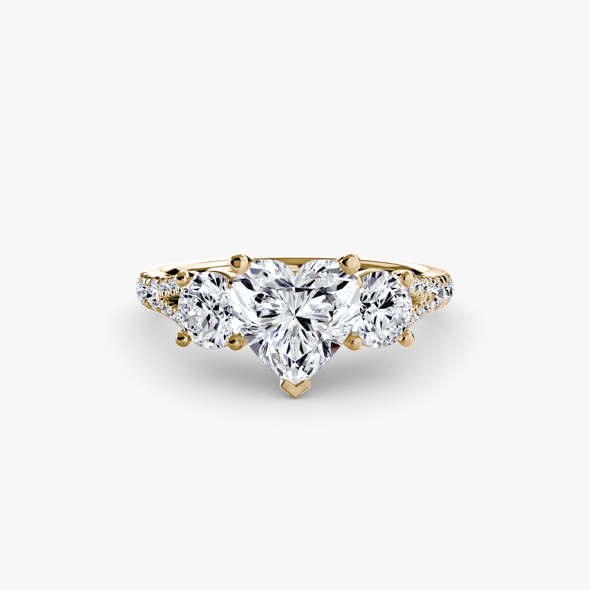 The MICHAEL ISAAC Three-Stone with Pavé Band 3 ring showcases a heart-shaped diamond between two round diamonds and pavé accent stones on a gold band, displayed on a plain white background.