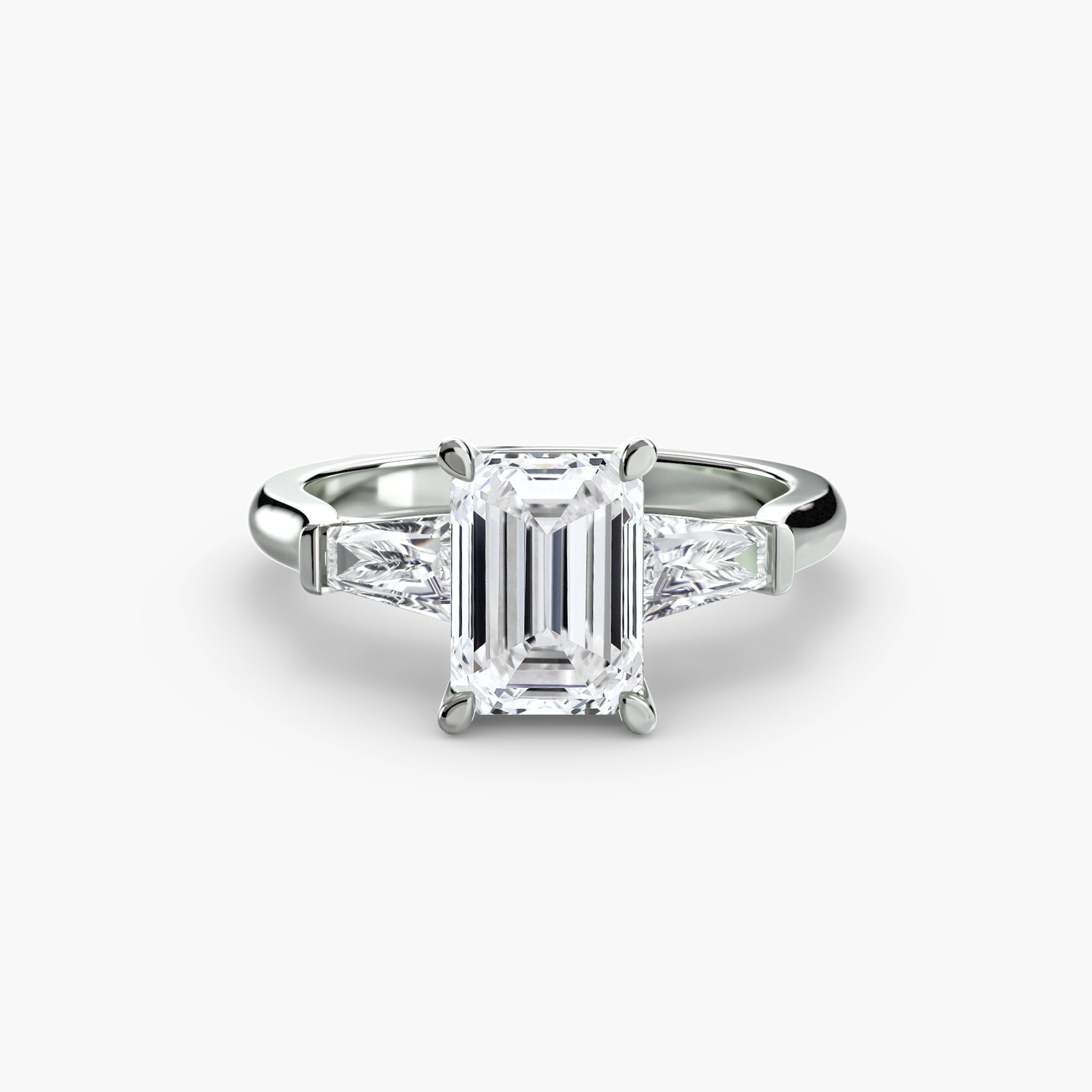 The MICHAEL ISAAC Three-Stone Ring features a central emerald-cut diamond with two baguette side stones, shown on a plain white background.