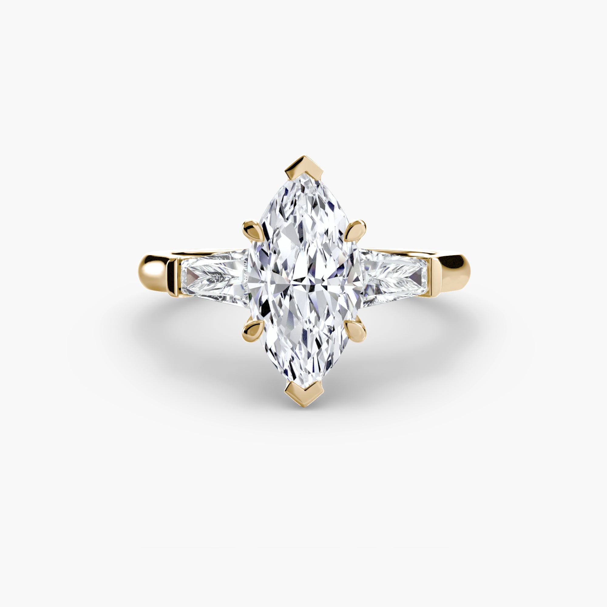 The MICHAEL ISAAC Three-Stone Ring features a gold band with a marquise-cut center diamond and two baguette side stones, displayed on a plain white background.