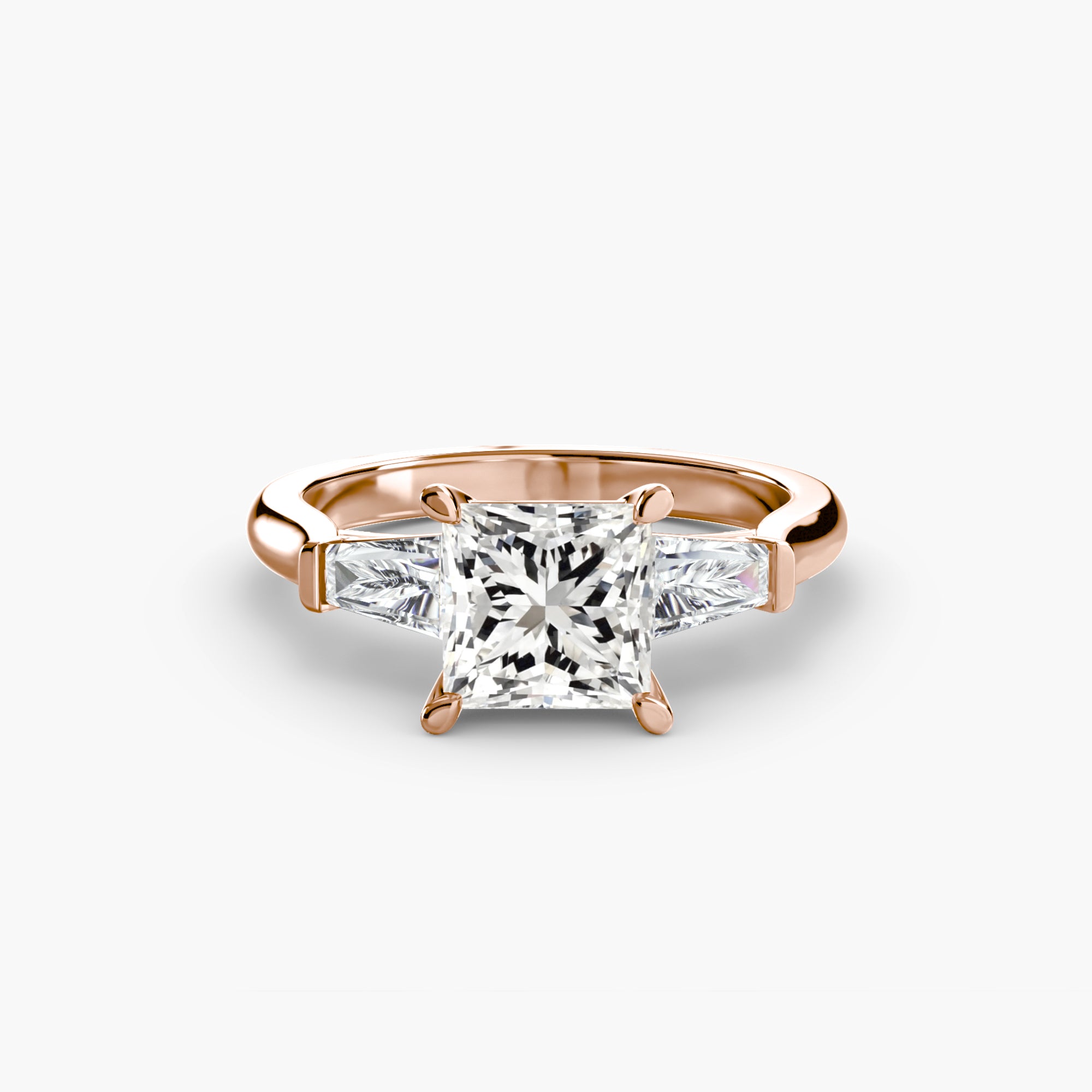 The MICHAEL ISAAC Three-Stone Ring features a rose gold band with a large square-cut center diamond and two baguette side stones, elegantly displayed on a plain white background.