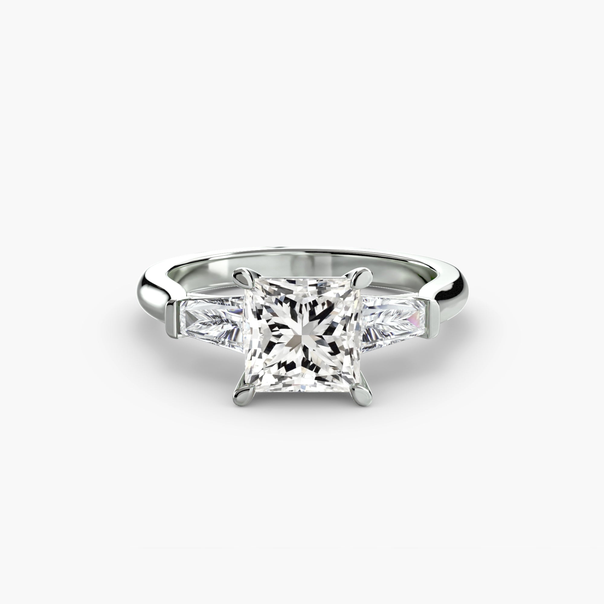 The MICHAEL ISAAC Three-Stone Ring features baguette side stones and a dazzling center diamond, creating a stunning design displayed on a white background.