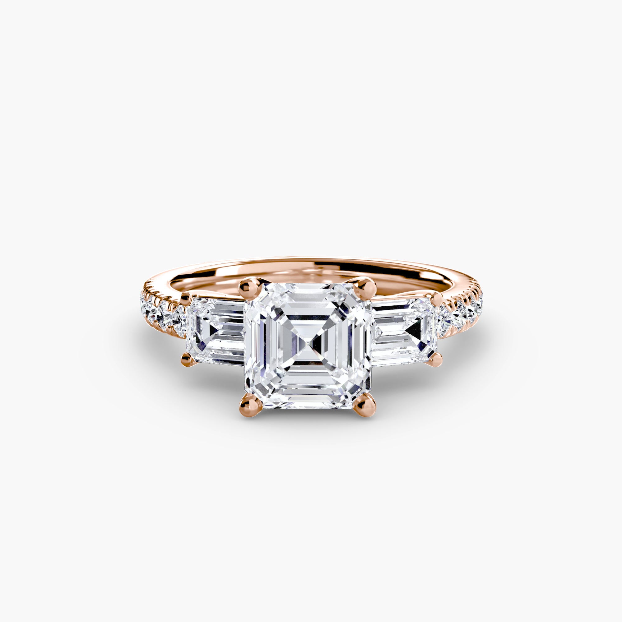 The MICHAEL ISAAC Three-Stone Ring with Pavé Band 4 features a rose gold setting, a large square-cut center diamond, two smaller rectangular side diamonds, and pavé accents, shown against a white background.